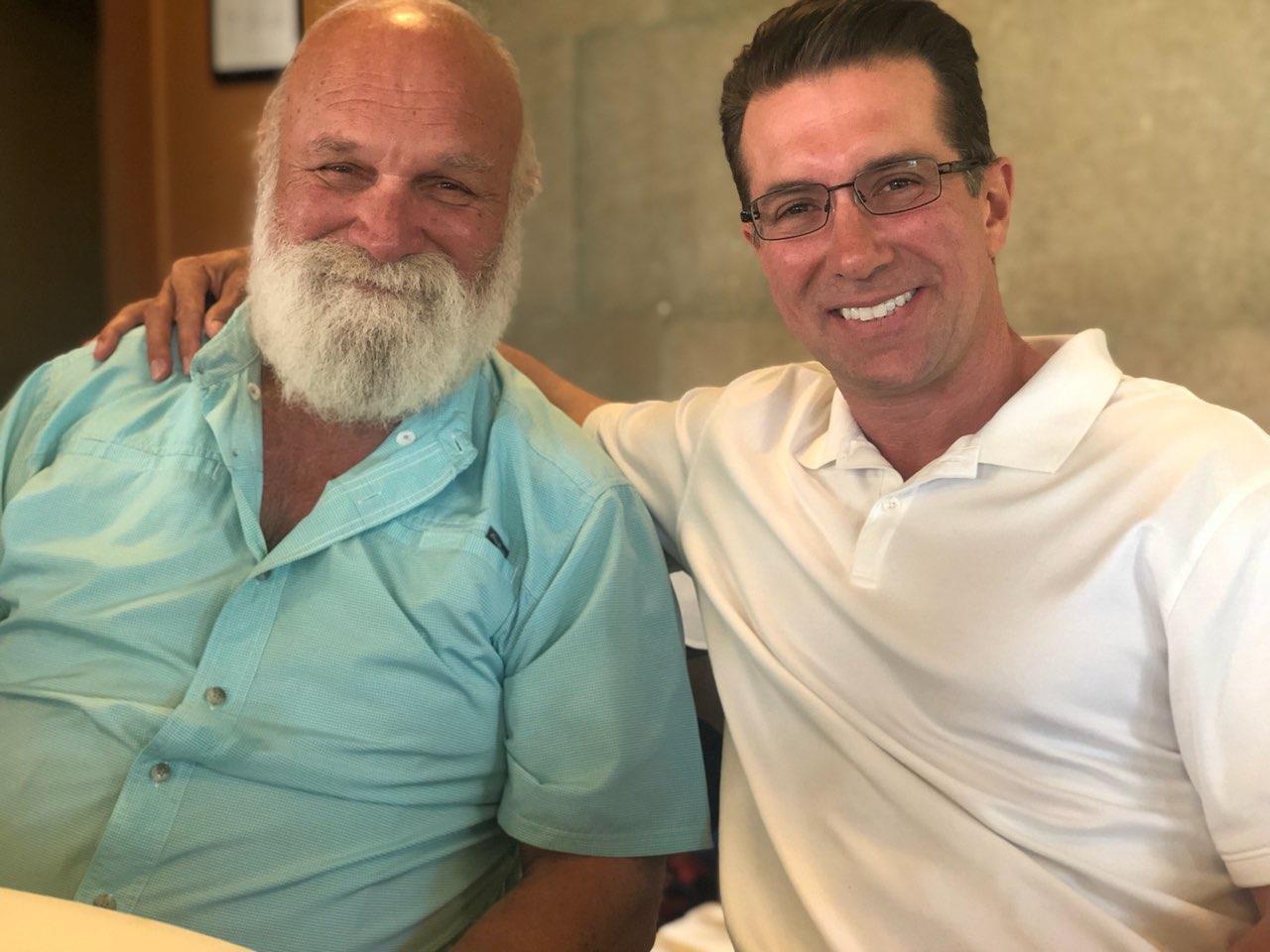 Andre in a light blue shirt with his arm around one of his sons