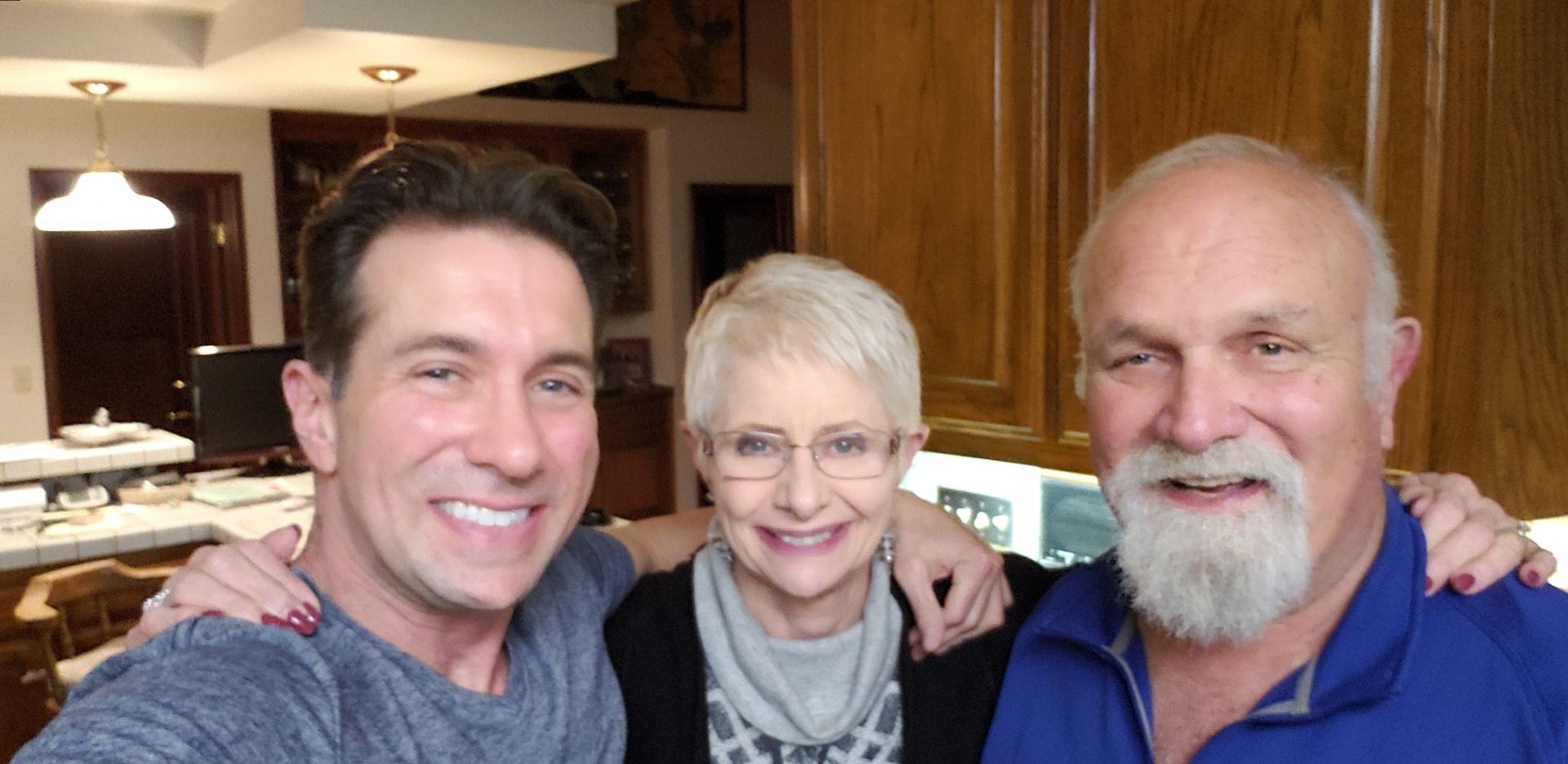Andre and Gloria smiling with one of their sons in the kitchen