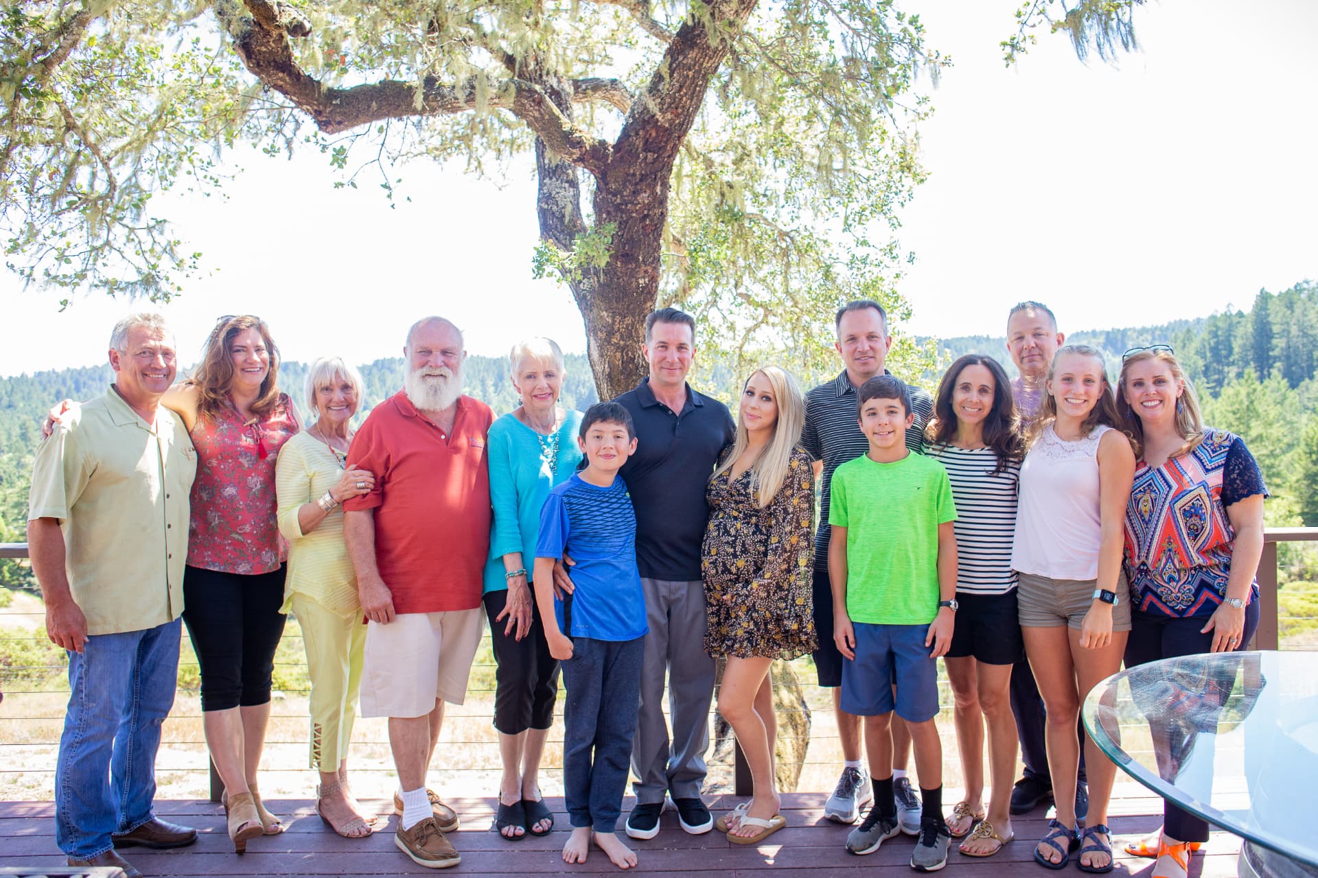 The Frere family gathered together on a wooden deck beneath a great oak tree