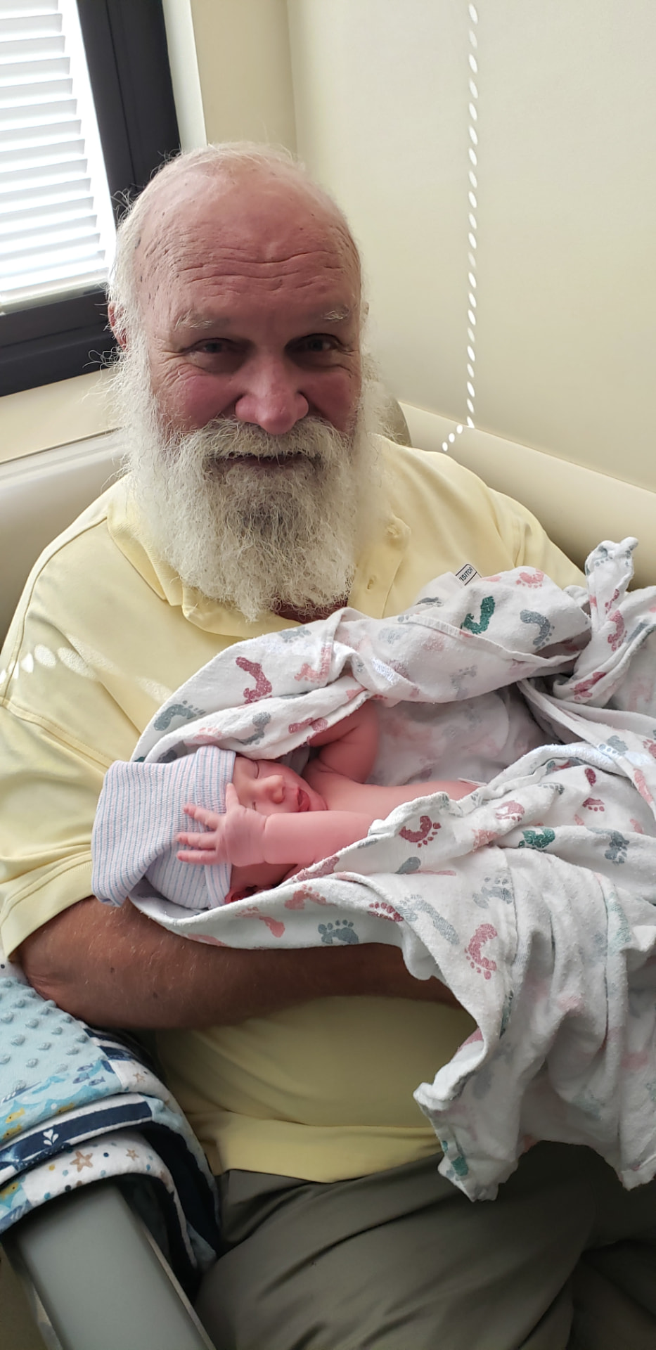 Andre holding a newborn grandchild wrapped in a blanket